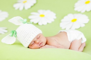 newborn baby girl sleeping on green meadow among flowers
